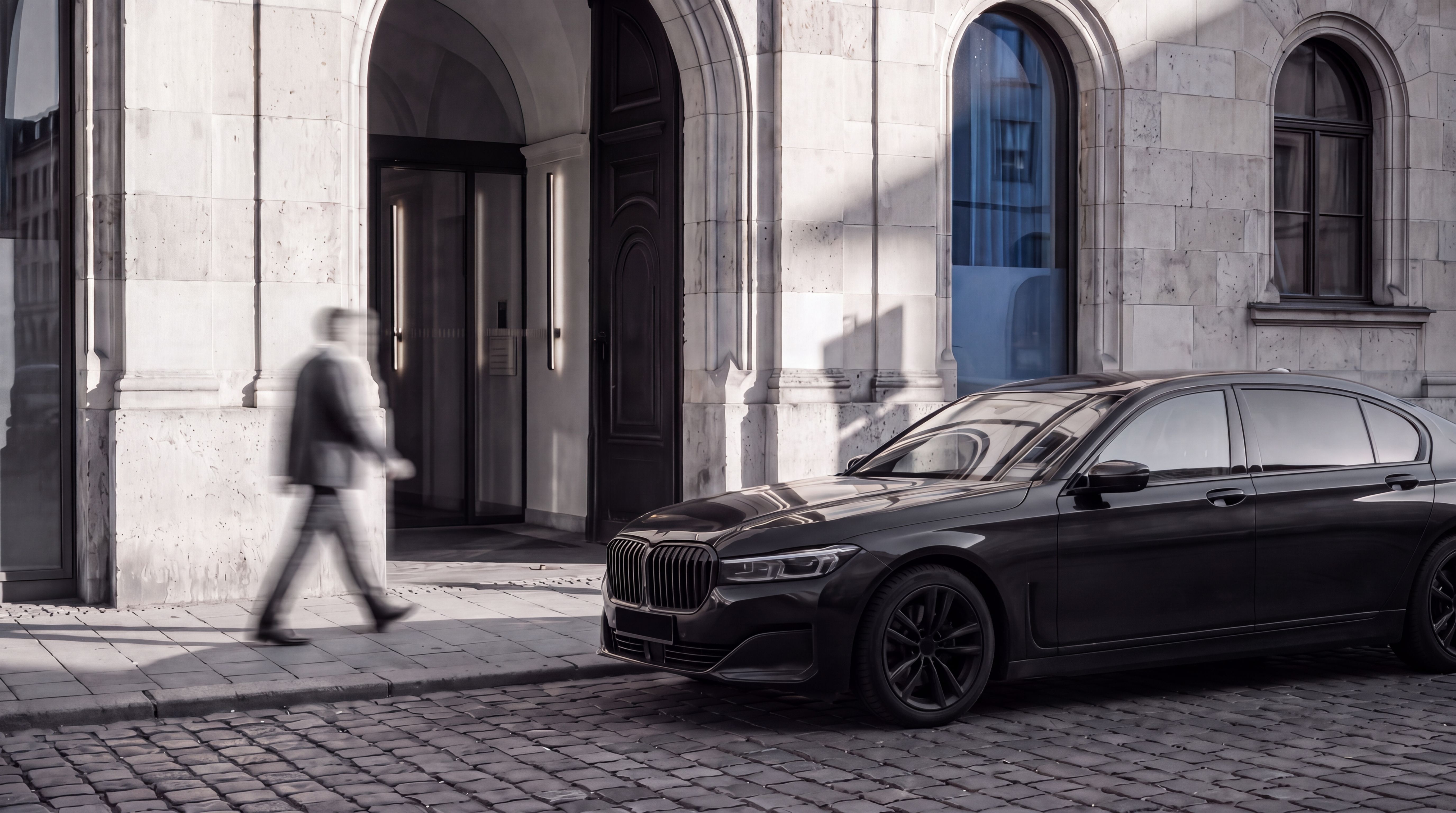 Dunkle Limousine vor dem Eingang eines historischen Gebäudes, eine Person geht vorbei